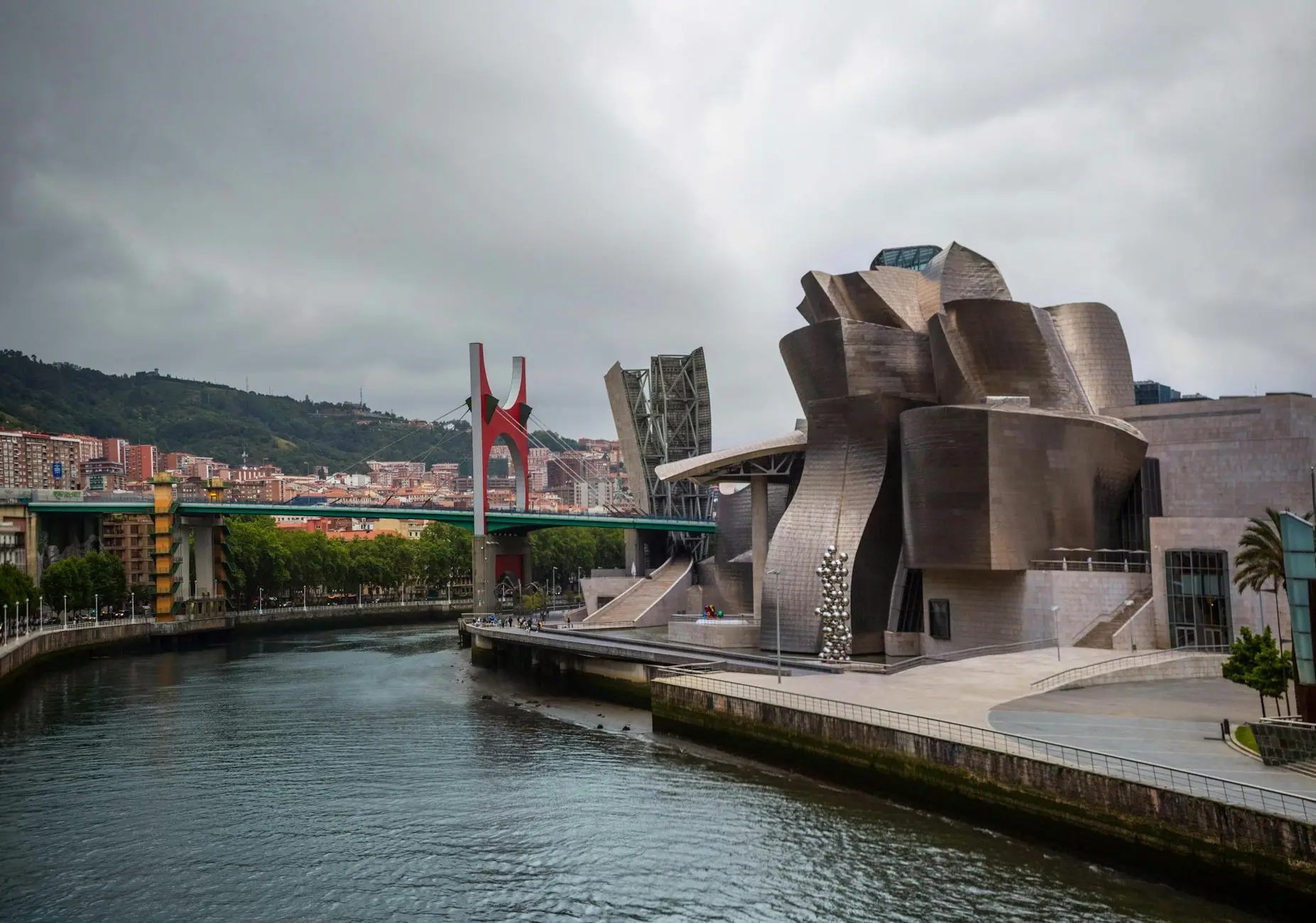 View of the Guggenheim Museum in Bilbao, featuring its unique architecture and surrounding landscape along the river.