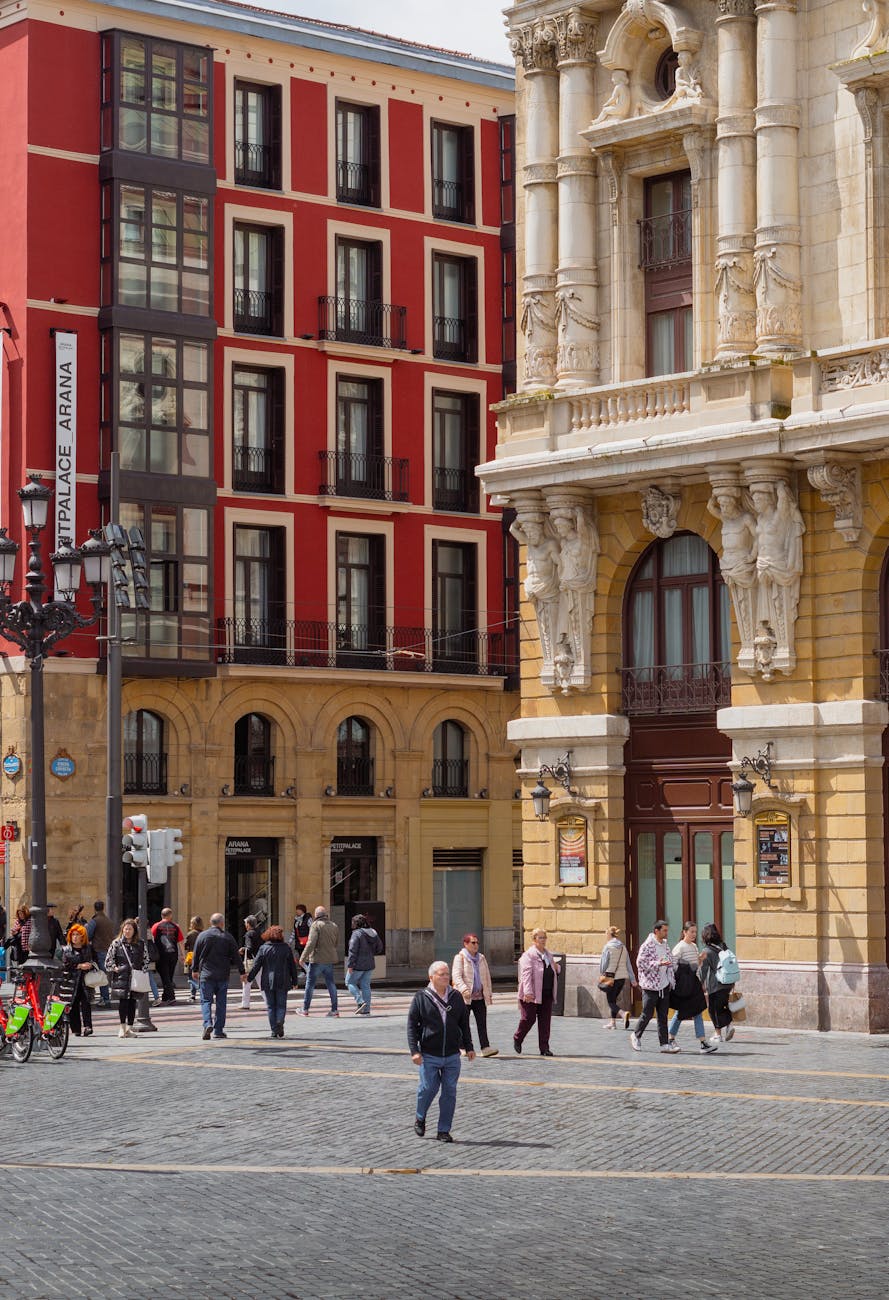 A bustling street scene in Bilbao, Spain, featuring a mix of modern and historical architecture, with pedestrians walking and enjoying the vibrant atmosphere.