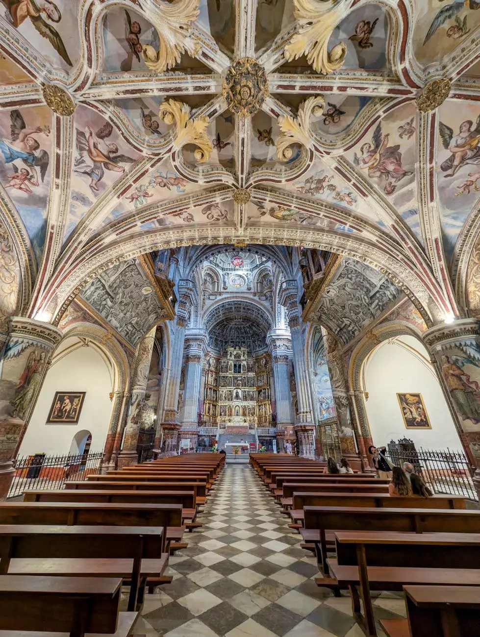 Interior view of a historic cathedral featuring intricate frescoes on the ceiling, ornate altar, and empty wooden pews leading towards the altar.